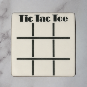 A square cookie, flooded in white icing and decorated with our Tic Tac Toe Game Cookie Stencil in black royal icing, BakeArt Stencils