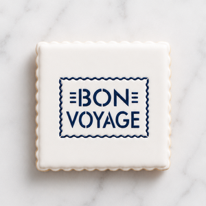 A white cookie with scalloped edges and flooded in white icing, decorated with our Bon Voyage Cookie Stencil in navy blue royal icing