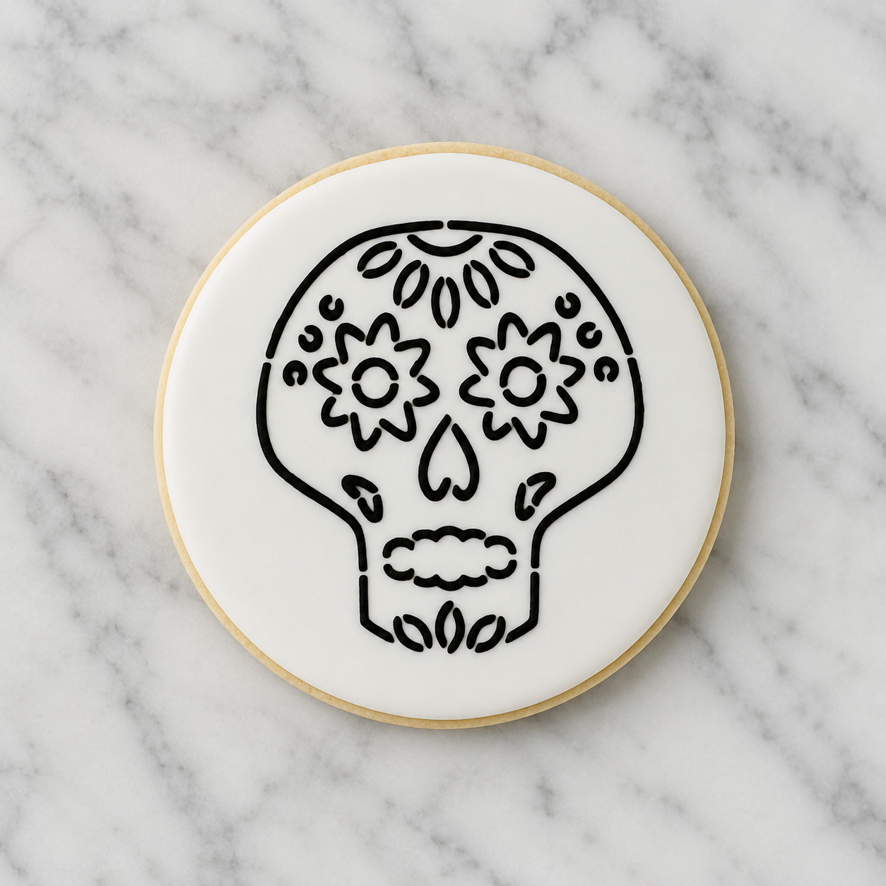  A white, round sugar cookie decorated with our Sugar Skull PYO Cookie Stencil in black royal icing and shown on a Carrara Marble countertop, BakeArt Stencils