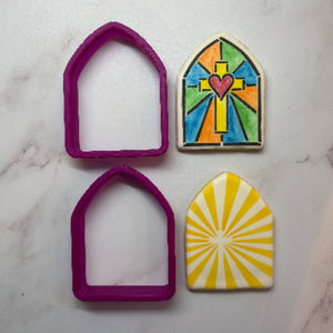 Pointed Arch Cookie Cutter shown with two of the shaped sugar cookies decorated with our Stained Glass and Cross Sunburst Cookie Stencils