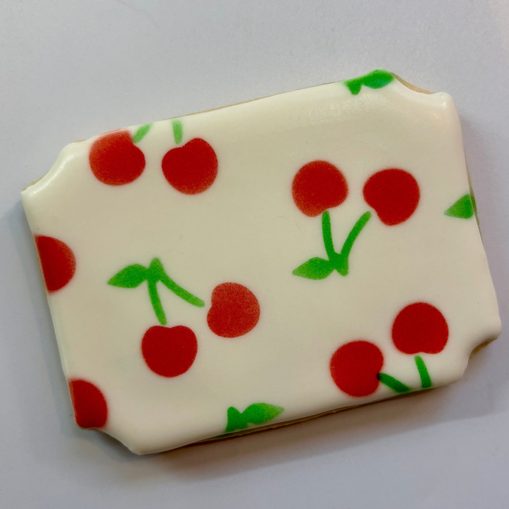 Cherry Pattern Stencil Set, Set of 2 airbrushed in red and green on a plaque   shaped sugar cookie.