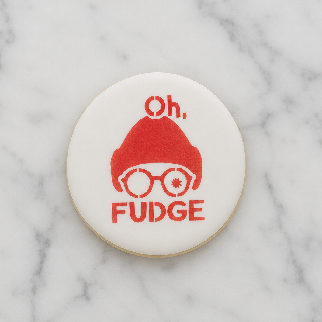 A white, round cookie decorated with the Oh Fudge Cookie Stencil in red and shown on a marble counter