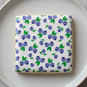 Square sugar cookie flooded in white royal icing and decorated with this Blueberries Cookie Stencil, a 3-piece set. 