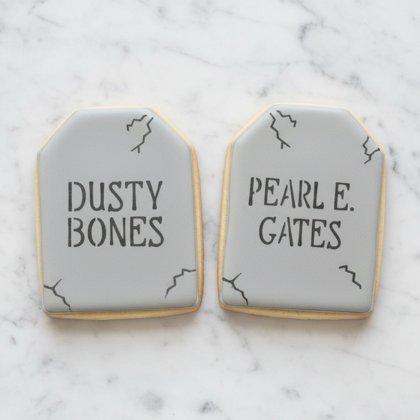 Two sugar cookies flooded in grey royal icing and stenciled with Dusty Bones and Pearl E. Gates designs, part of the Tombstone Cookie Cutter and stencil set at BakeArt Stencils